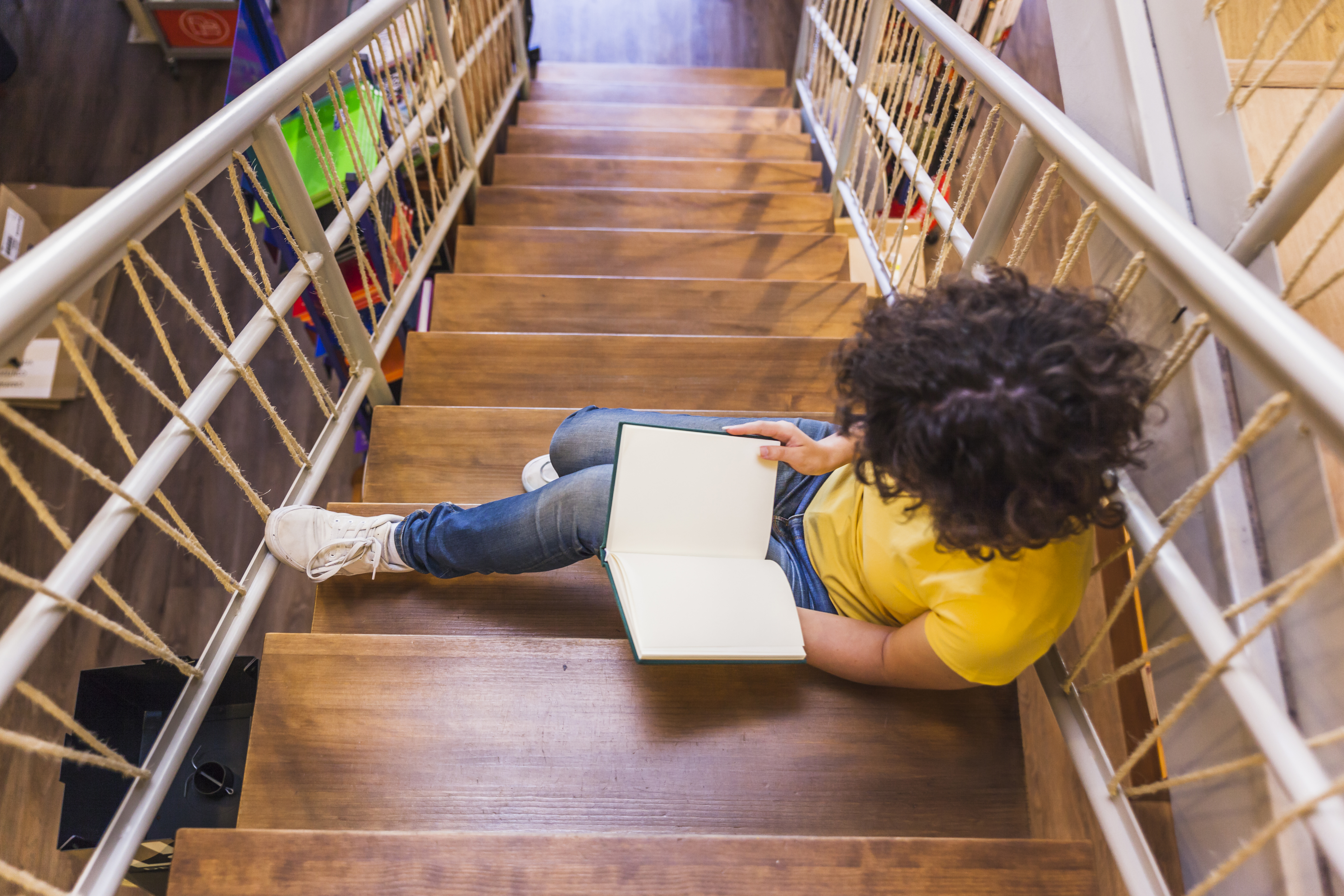 Learner reading on a wooden staircase, symbolizing growth along programs and pathways.